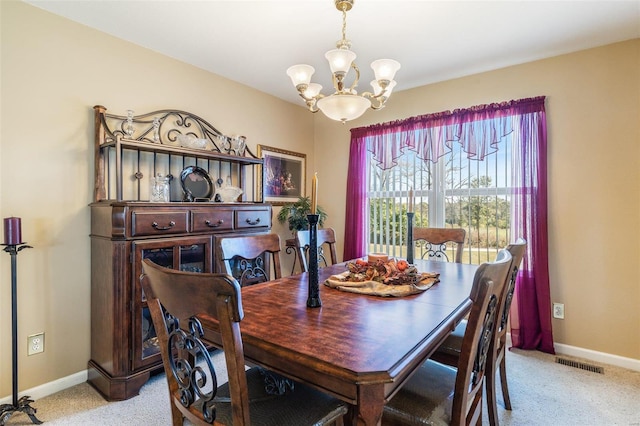 dining space featuring light carpet and an inviting chandelier