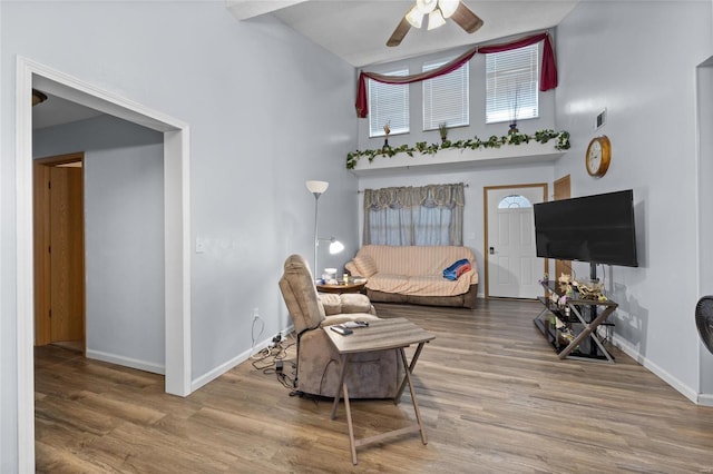 living room featuring a towering ceiling, hardwood / wood-style flooring, and ceiling fan