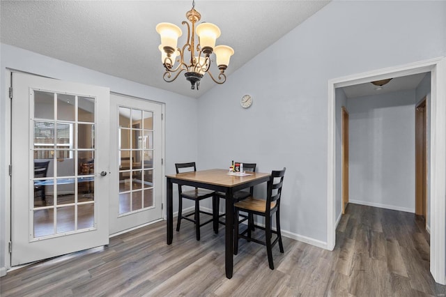 dining room with wood-type flooring, a textured ceiling, french doors, and a notable chandelier