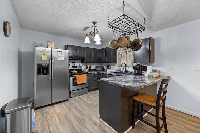 kitchen featuring a breakfast bar, light hardwood / wood-style floors, stainless steel appliances, and an inviting chandelier