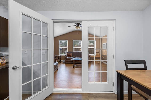 doorway featuring a textured ceiling, ceiling fan, dark hardwood / wood-style flooring, and vaulted ceiling