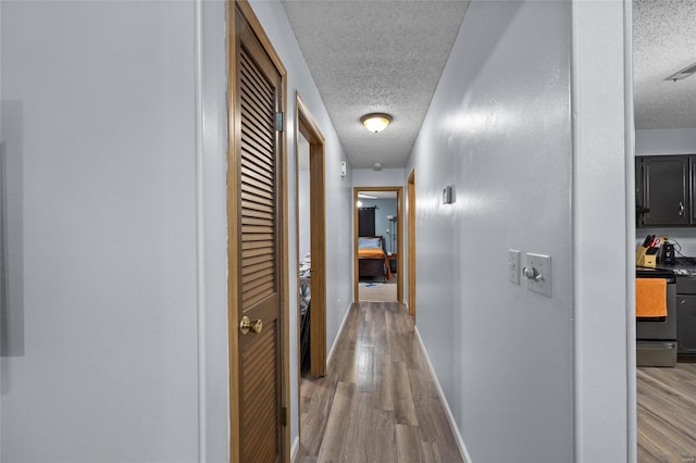 hall with light hardwood / wood-style floors and a textured ceiling