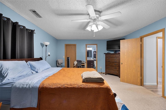 bedroom with a textured ceiling, light colored carpet, and ceiling fan