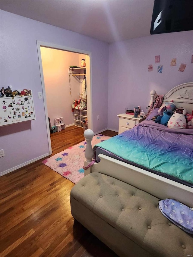 bedroom with wood-type flooring and a walk in closet