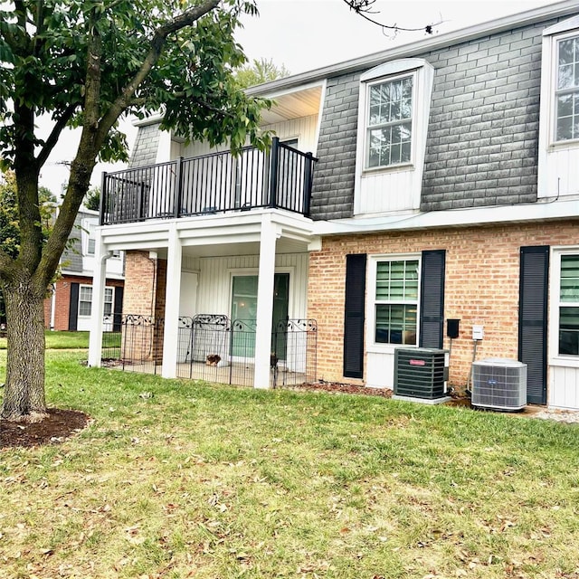 rear view of house featuring a balcony, a yard, and central air condition unit