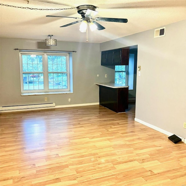 unfurnished room with ceiling fan, a baseboard radiator, light wood-type flooring, and a textured ceiling