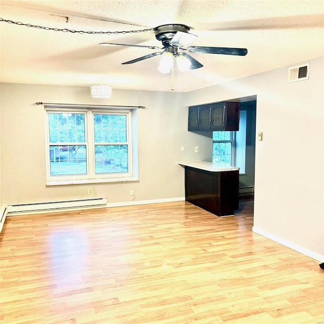 empty room with ceiling fan, a baseboard radiator, light wood-type flooring, and a textured ceiling