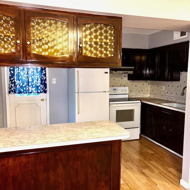 kitchen with light hardwood / wood-style floors, decorative backsplash, white appliances, and sink