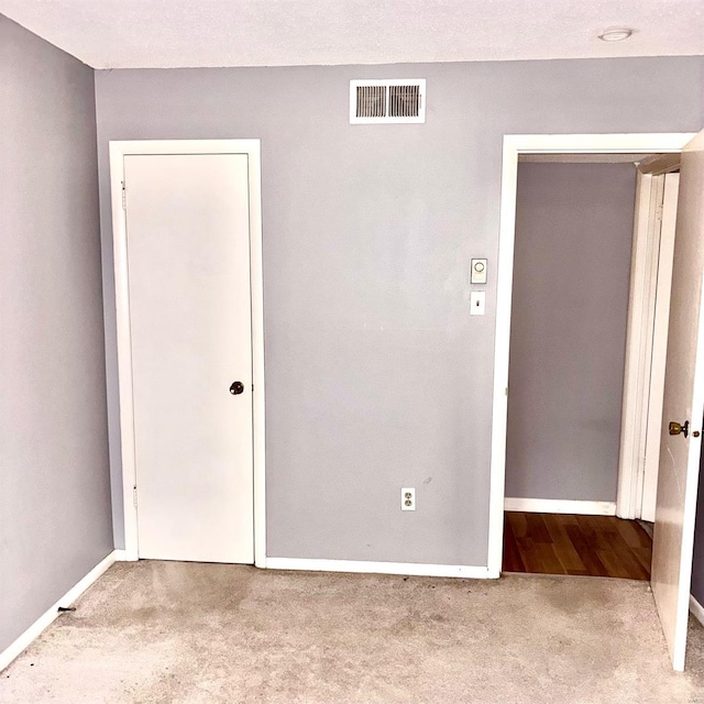 unfurnished bedroom featuring a textured ceiling and light carpet