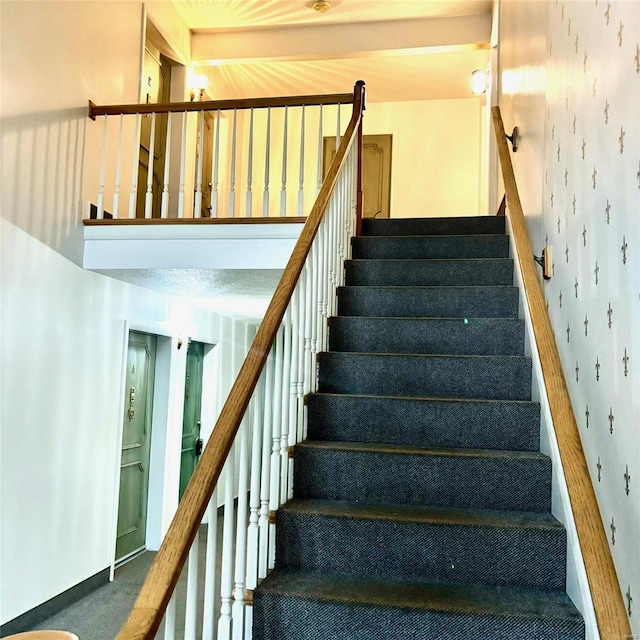 stairs featuring carpet floors and beamed ceiling