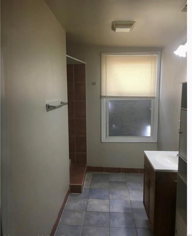 bathroom featuring walk in shower, vanity, and tile patterned flooring