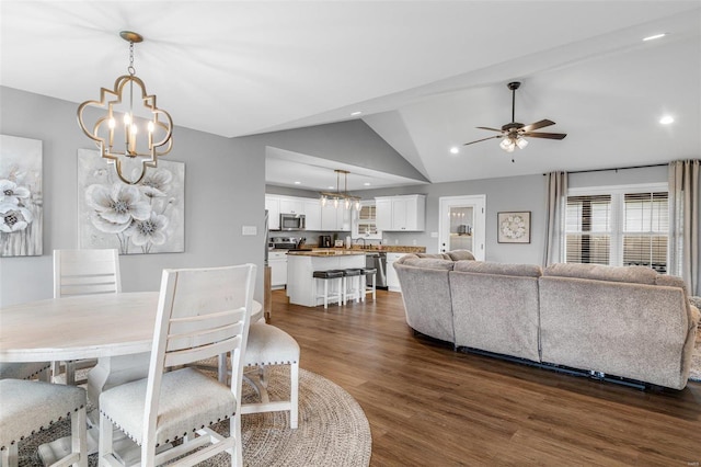 dining space featuring ceiling fan with notable chandelier, lofted ceiling, dark hardwood / wood-style floors, and sink