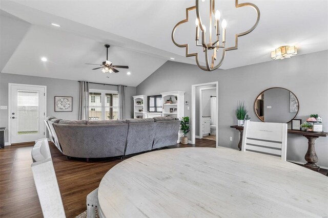 dining space with ceiling fan with notable chandelier, dark wood-type flooring, and lofted ceiling