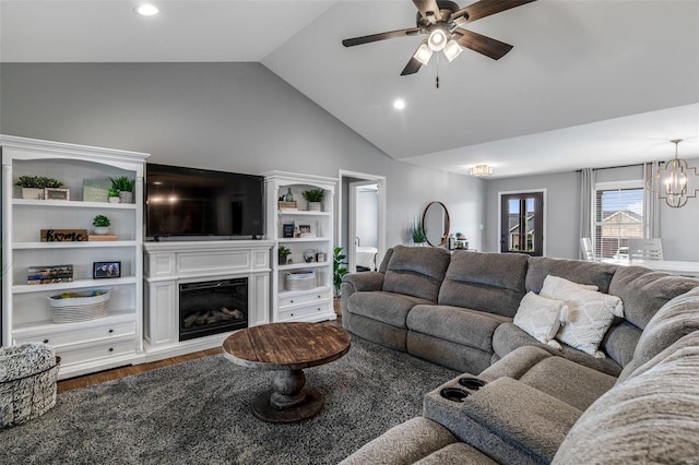 living room featuring ceiling fan with notable chandelier, vaulted ceiling, and dark wood-type flooring