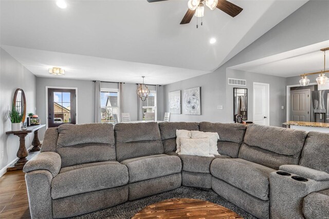 living room with ceiling fan with notable chandelier, lofted ceiling, and dark wood-type flooring