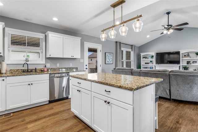 kitchen with ceiling fan, white cabinets, stainless steel dishwasher, vaulted ceiling, and hardwood / wood-style floors