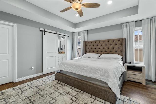 bedroom with ceiling fan, dark wood-type flooring, and a barn door