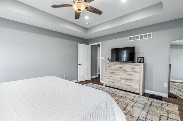 bedroom featuring ceiling fan, a tray ceiling, and dark hardwood / wood-style floors