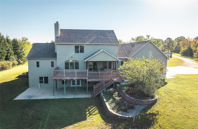 rear view of house featuring a wooden deck, a lawn, and a patio