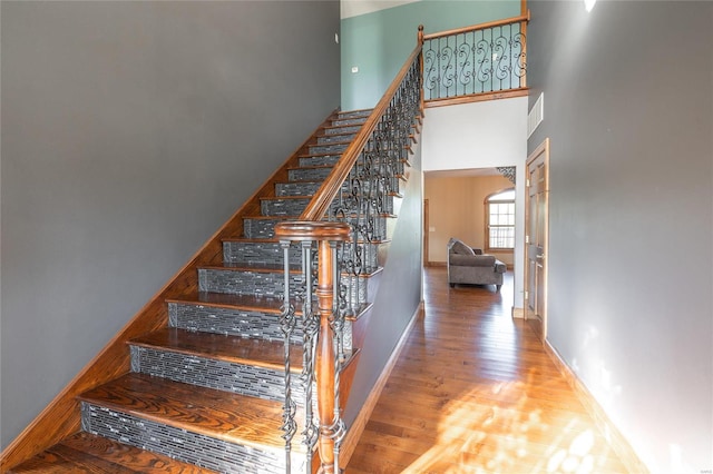 stairway featuring wood-type flooring and a high ceiling