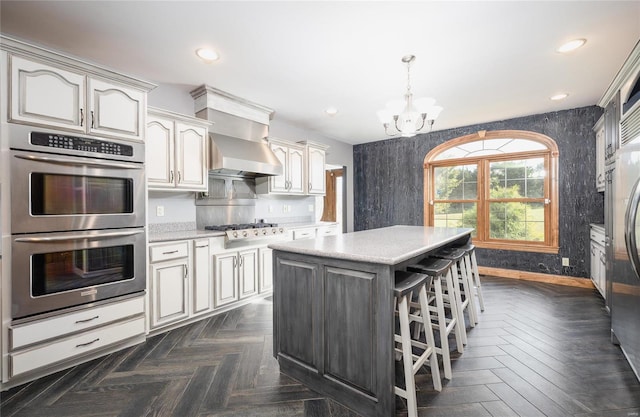 kitchen with a notable chandelier, hanging light fixtures, a kitchen island, appliances with stainless steel finishes, and dark parquet floors