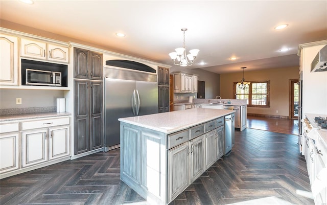 kitchen with dark parquet floors, decorative light fixtures, stainless steel appliances, a center island, and an inviting chandelier