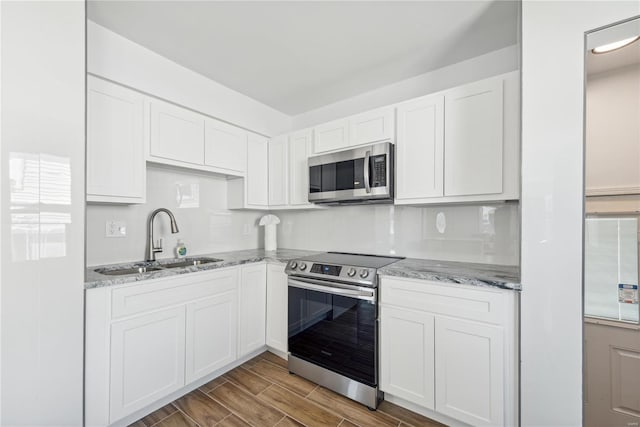 kitchen with stainless steel appliances, white cabinetry, light hardwood / wood-style floors, and sink