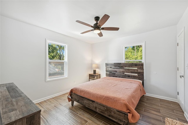 bedroom with multiple windows, wood-type flooring, and ceiling fan