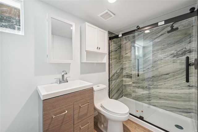 bathroom featuring wood-type flooring, a shower with door, vanity, and toilet