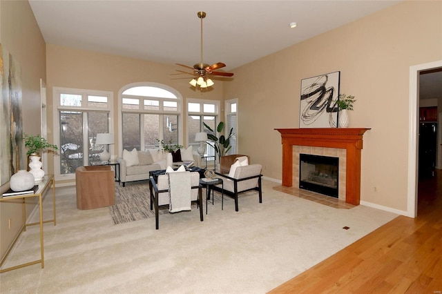 living room featuring ceiling fan, a fireplace, and light carpet