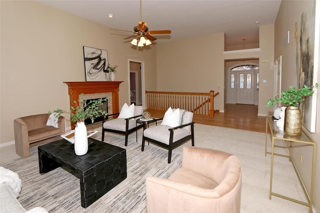 carpeted living room featuring ceiling fan and a tiled fireplace