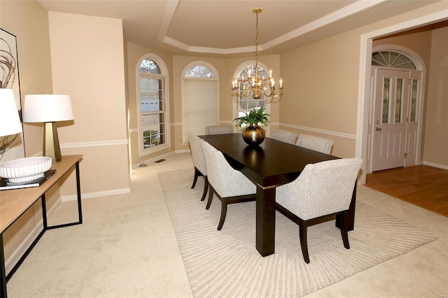 carpeted dining room with a notable chandelier and a raised ceiling