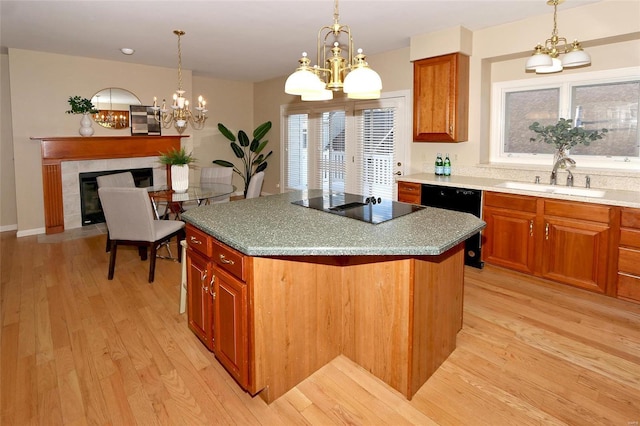 kitchen with a tile fireplace, sink, a kitchen island, and black appliances