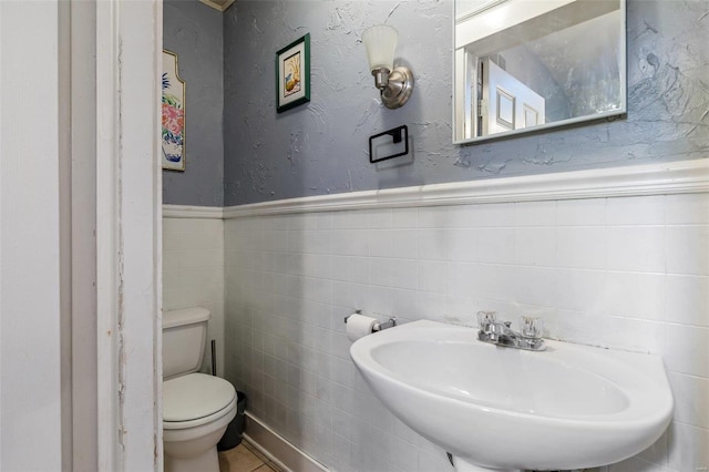 bathroom with sink, tile walls, and toilet