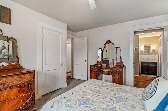 carpeted bedroom featuring ceiling fan, ensuite bath, crown molding, and sink