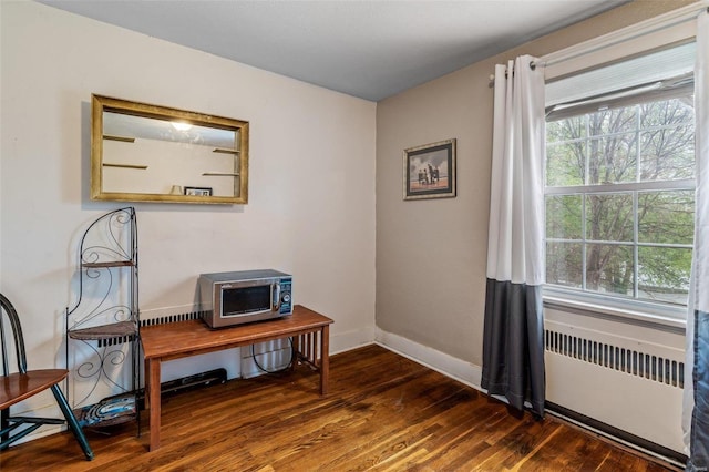 interior space with dark wood-type flooring and radiator heating unit