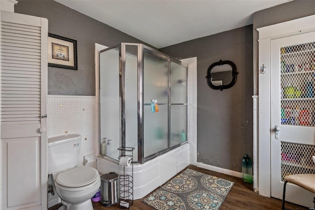 bathroom with combined bath / shower with glass door, hardwood / wood-style floors, and toilet