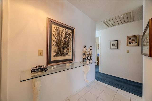 corridor featuring light tile patterned flooring and a textured ceiling