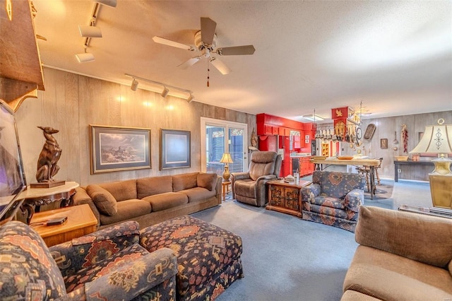 living room with carpet flooring, wooden walls, ceiling fan, and track lighting