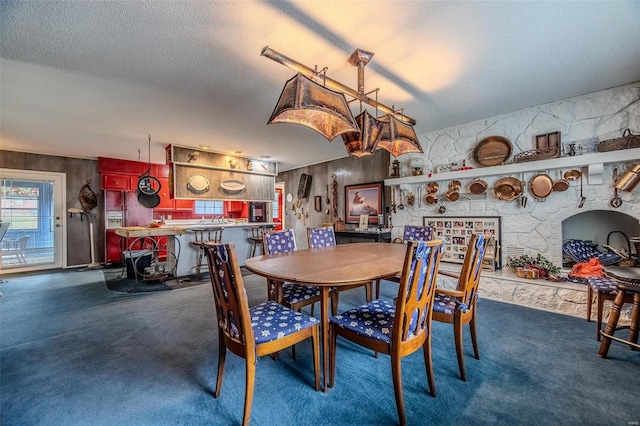 dining room featuring a textured ceiling, a fireplace, and dark carpet