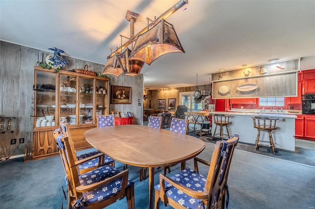 dining area featuring a textured ceiling and dark colored carpet