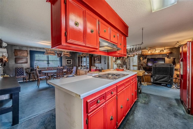 kitchen featuring stainless steel gas stovetop, dark carpet, and a textured ceiling