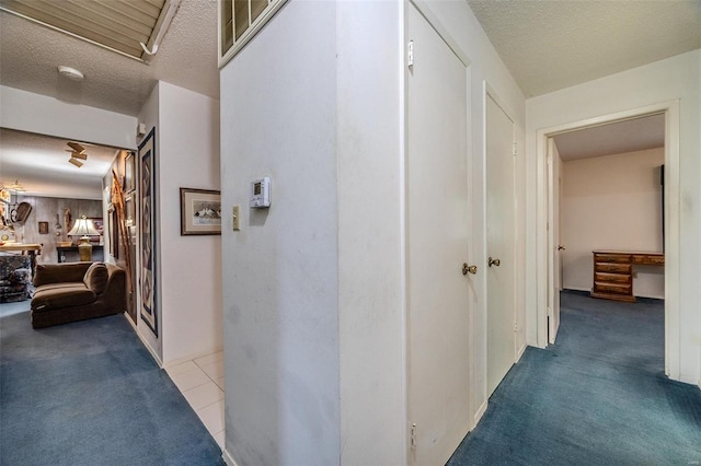 hall featuring light carpet and a textured ceiling