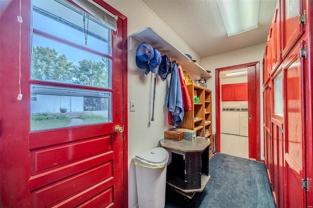 mudroom with a textured ceiling, washing machine and clothes dryer, and tile patterned floors