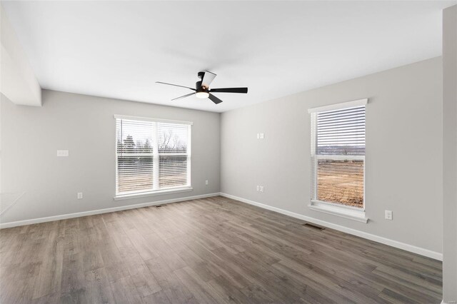 empty room with plenty of natural light, visible vents, wood finished floors, and ceiling fan