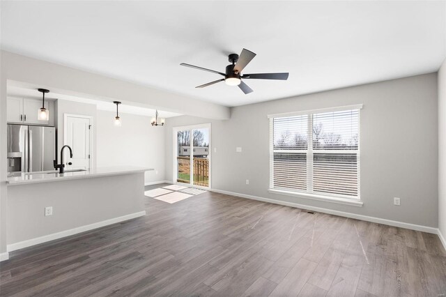 unfurnished living room featuring wood-type flooring, sink, and ceiling fan