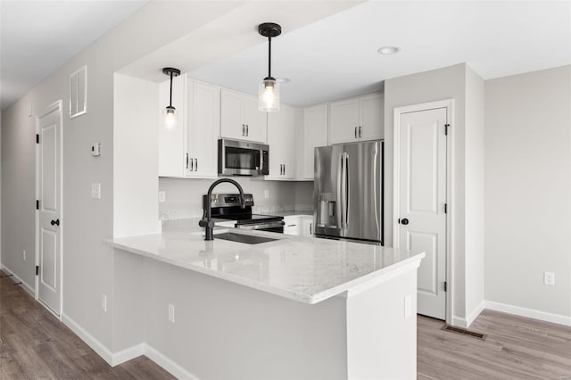 kitchen with visible vents, a peninsula, light stone countertops, stainless steel appliances, and light wood-style floors