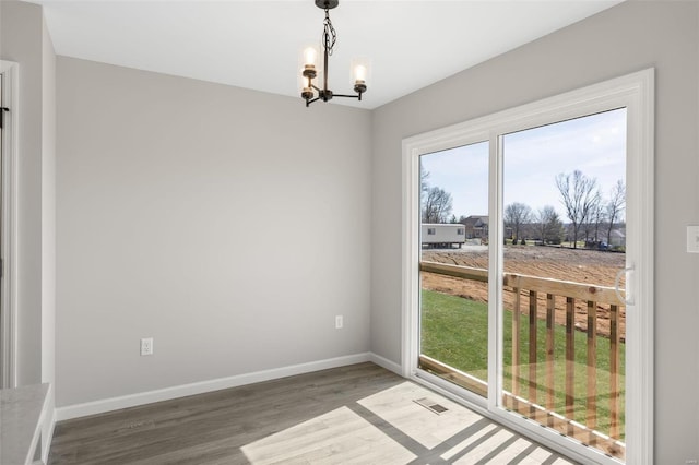 interior space with a notable chandelier, baseboards, and wood finished floors
