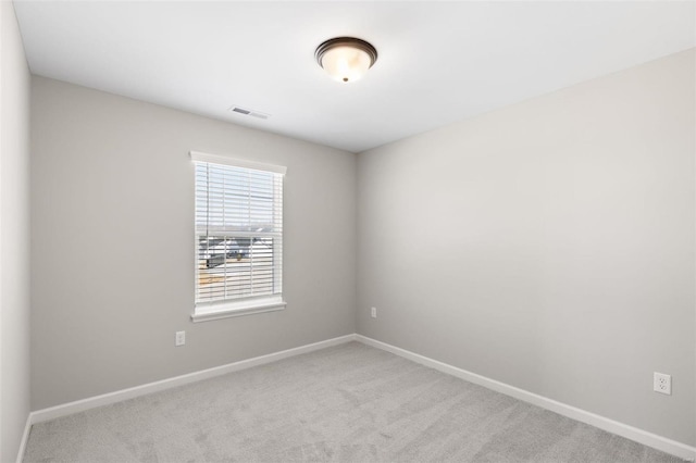 carpeted spare room featuring baseboards and visible vents