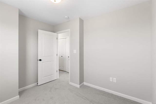 unfurnished room featuring light carpet and baseboards